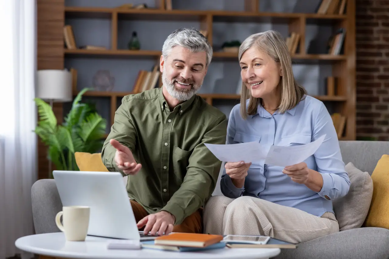 Senior couple sitting on a sofa discussing financial documents
